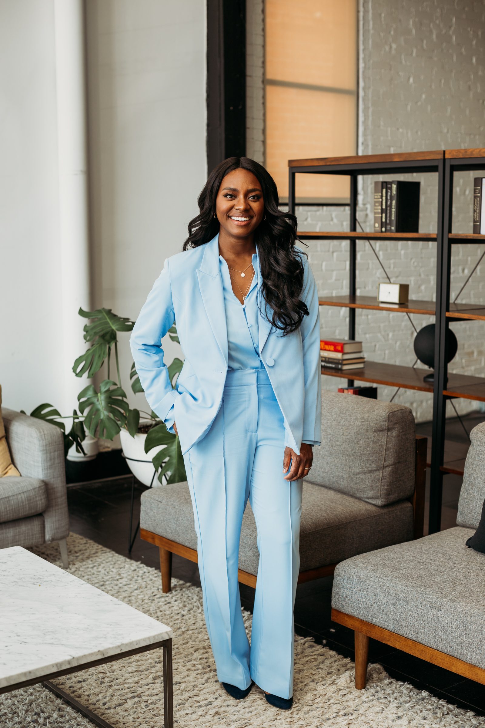Danielle standing in a light blue suit in a bright loft interior