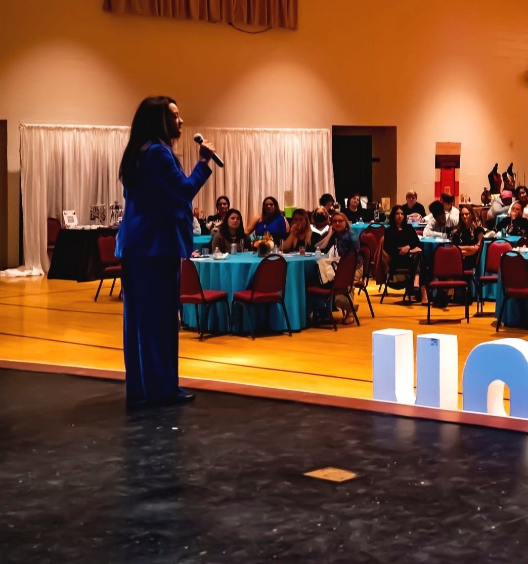 Danielle speaking on stage to a seated audience